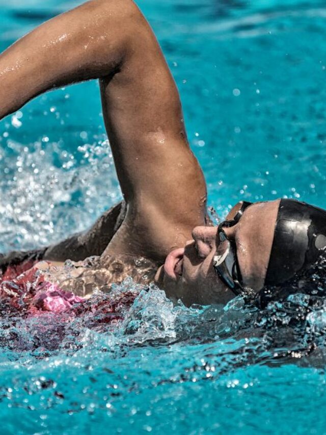 mulher nadando em piscina, com touca e óculos