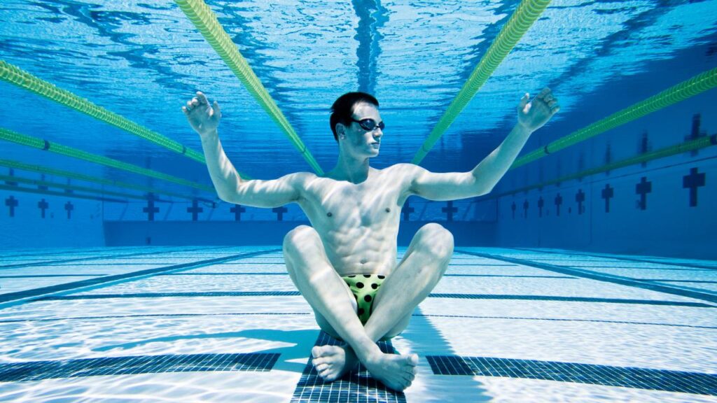 homem sentado no fundo de uma piscina